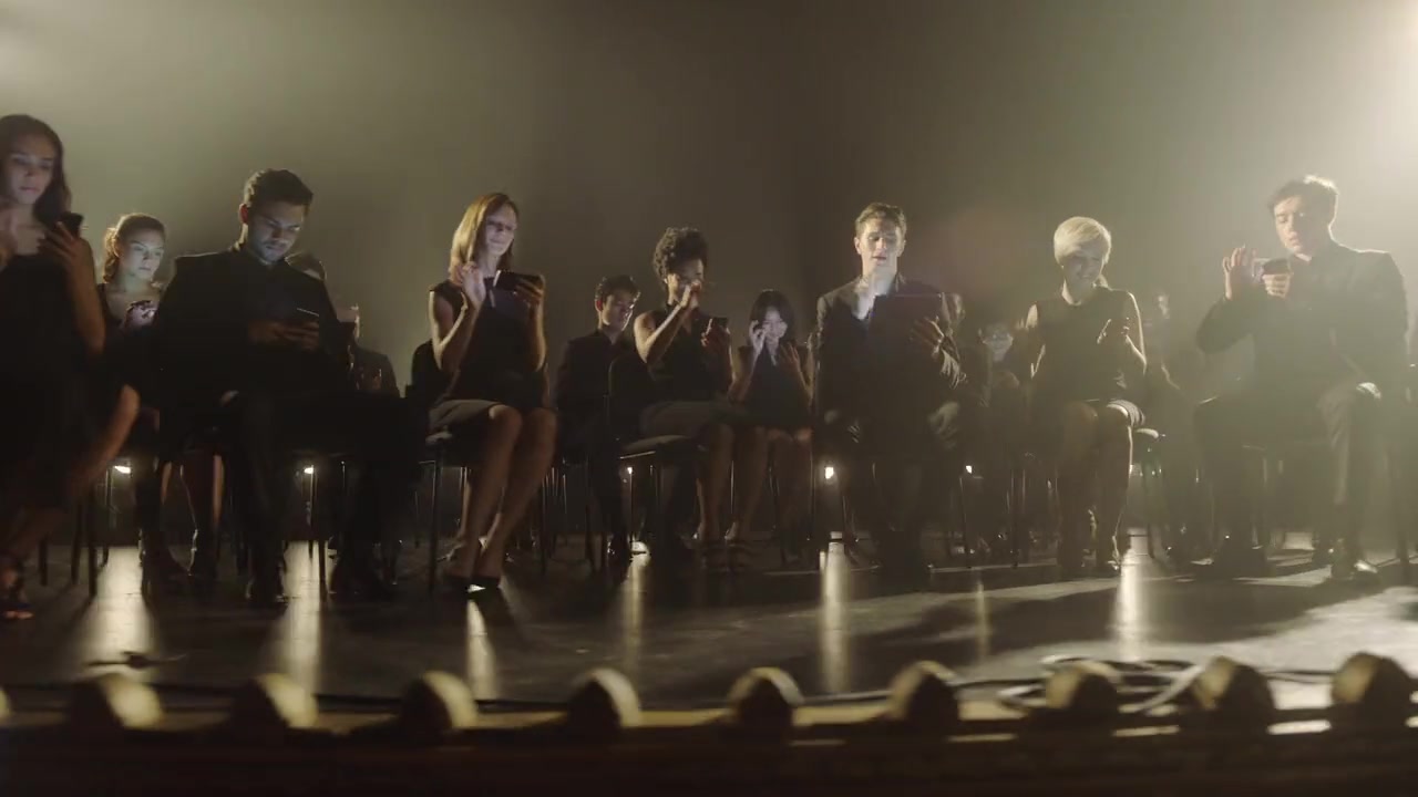 The Yahoo Mobile Symphony ensemble performing with synchronized mobile devices under stage lights.